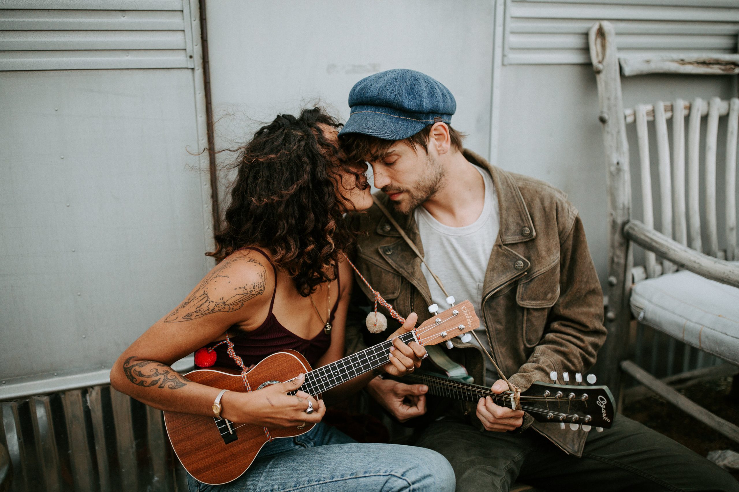 tattooed couple playing the uckele by an airstream trailer