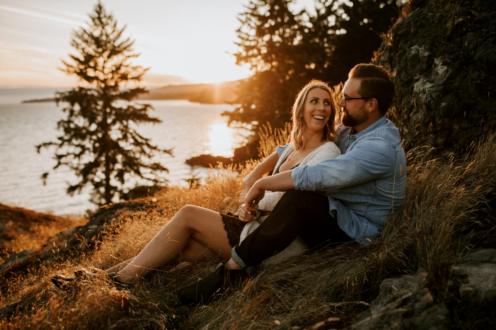 couple sitting on a rock at sunset at east sooke park in BC