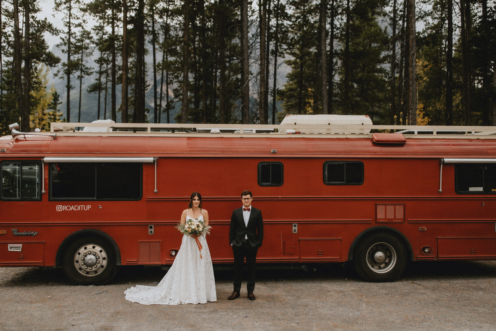 couple stands in front of a bus on their wedding day in the mountains of canmore alberta