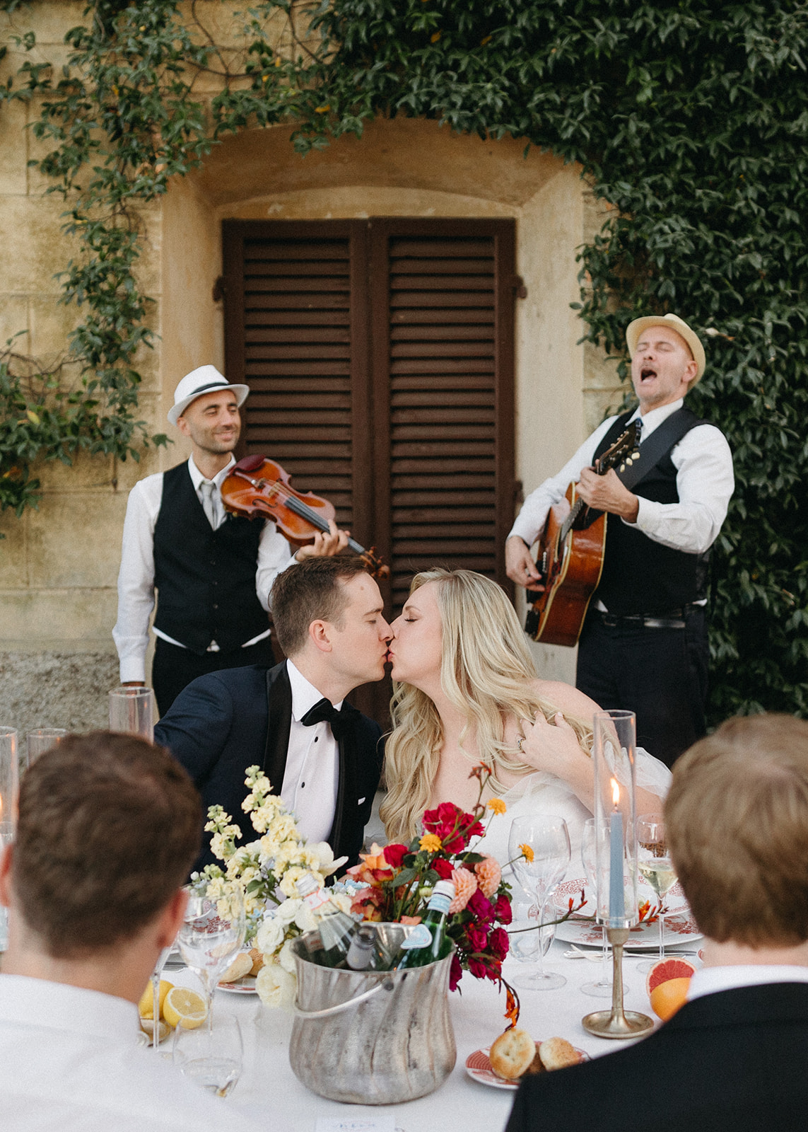 bride and groom kissing during long table wedding reception dinner in Tuscany, Italy